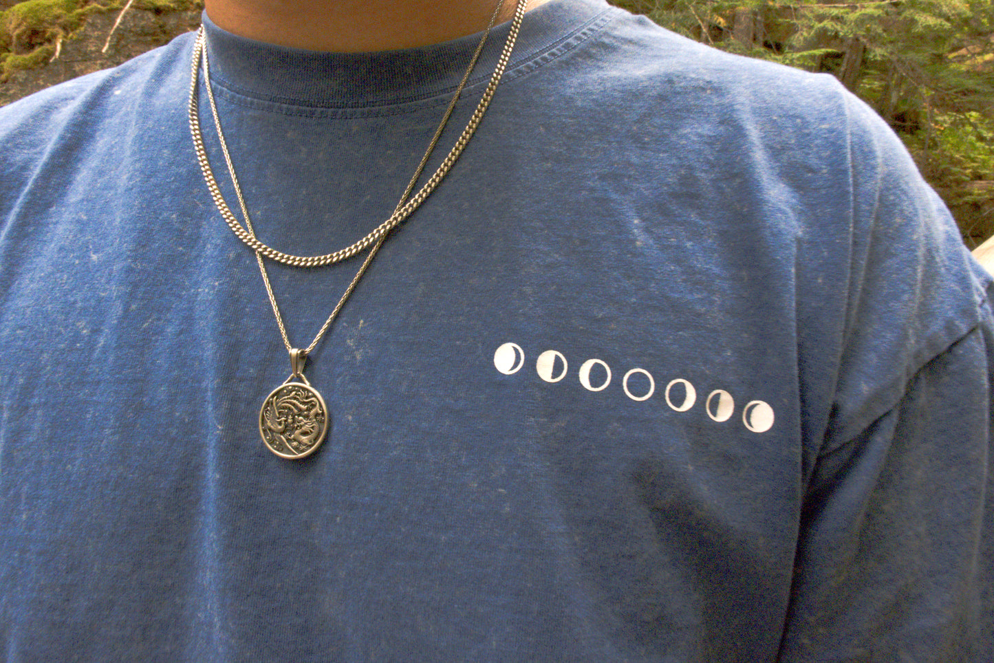 Person wearing a blue t-shirt with moon phases. Outdoors.