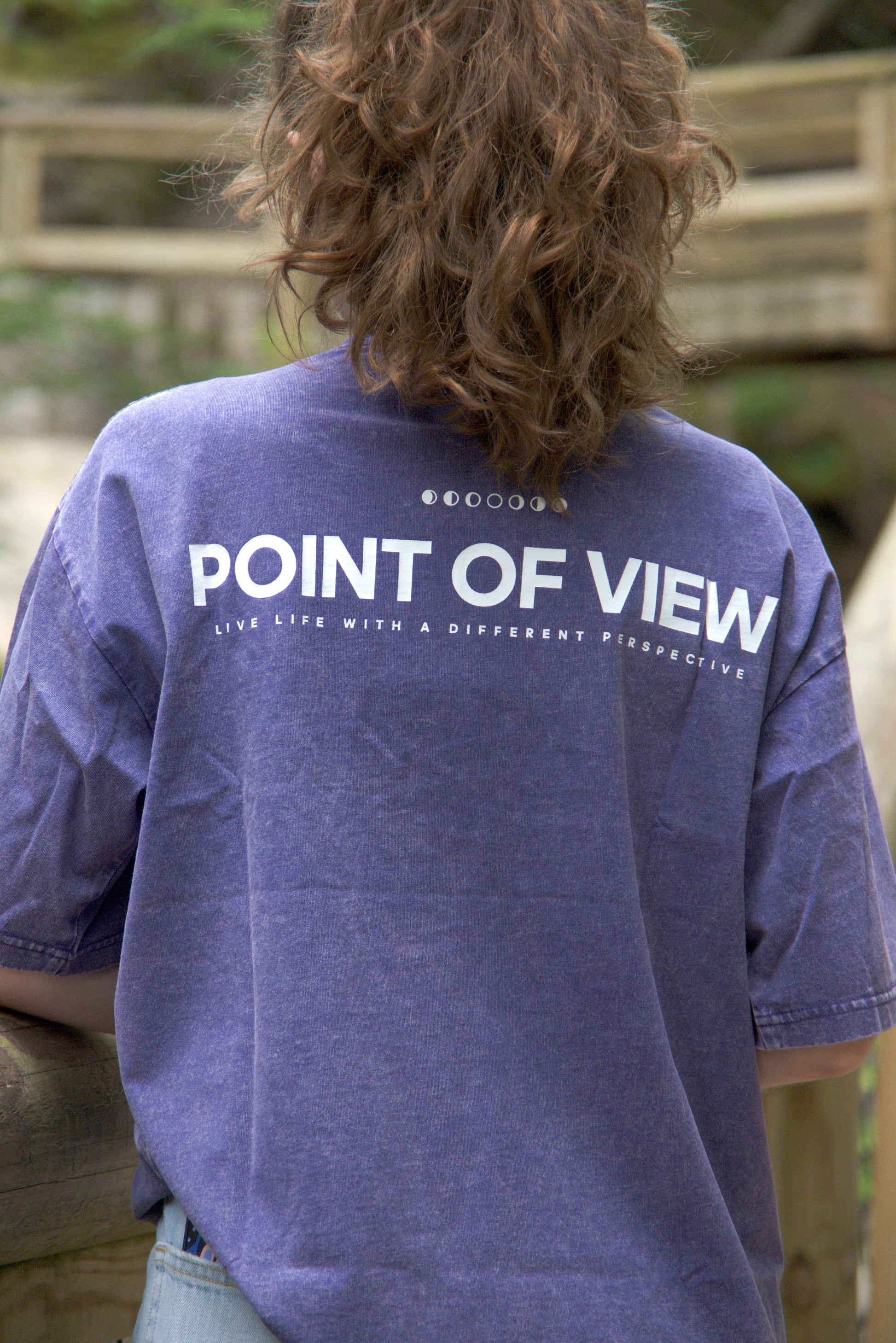 Person wearing a purple t-shirt with 'POINT OF VIEW LIVE LIFE WITH A DIFFERENT PERSPECTIVE' on the back.
